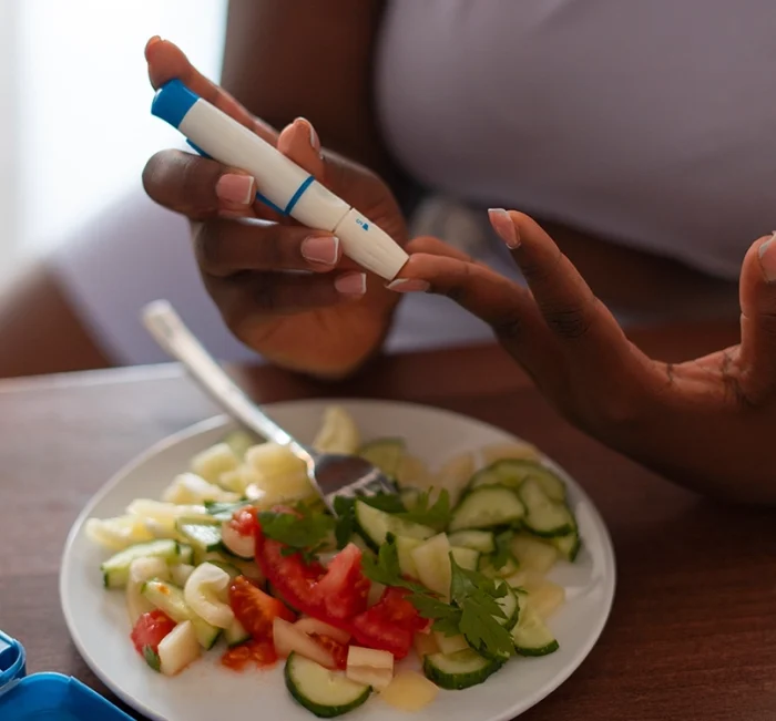 Person checking glucose levels beside a healthy meal